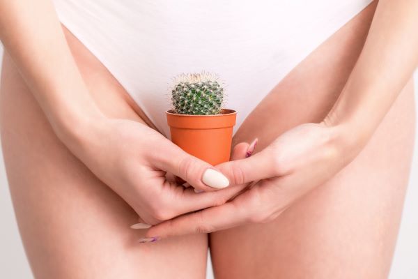 A flacidez íntima é um problema que aflige muitas mulheres. Na imagem, uma mulher segura um vasinho com um mini cacto, representando o incômodo causado pela condição.