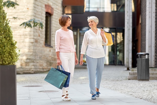 Duas mulheres maduras e descoladas passeiam pelas ruas do bairro e fazem compras nas lojas. 