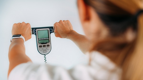 Médica segurando um aparelho de bioimpedância.